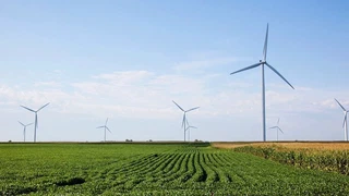 Wind turbines standing in farmland under a clear sky.