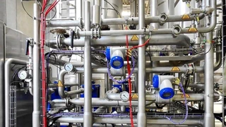 Stainless-steel process piping with valves and pressure gauges at an industrial plant.